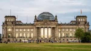 Das historische Reichstagsgebäude mit Glaskuppel in Berlin unter einem weitläufigen, blauen Sommerhimmel.