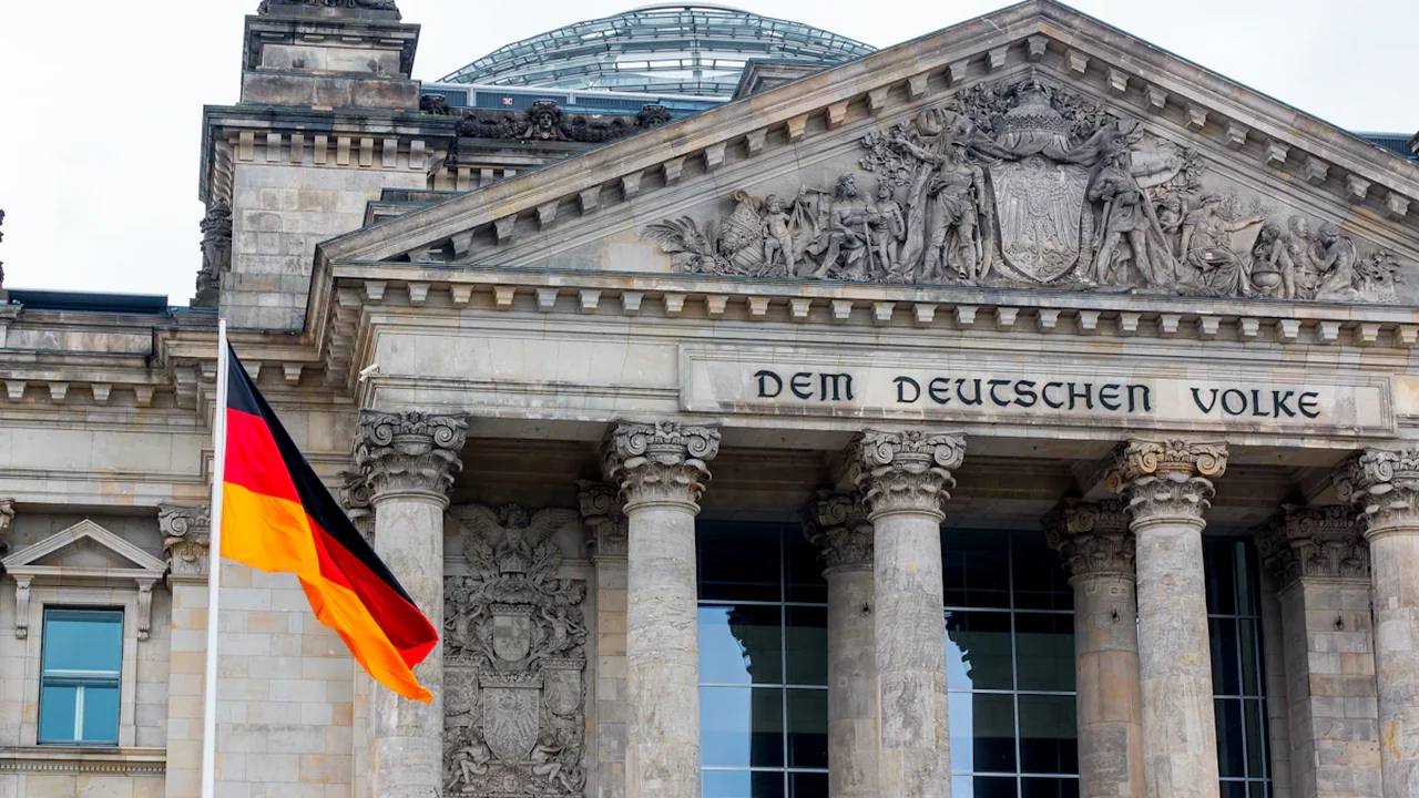 Nahaufnahme des Reichstagsgebäudes mit wehender deutscher Flagge vor dem historischen Gebäude.