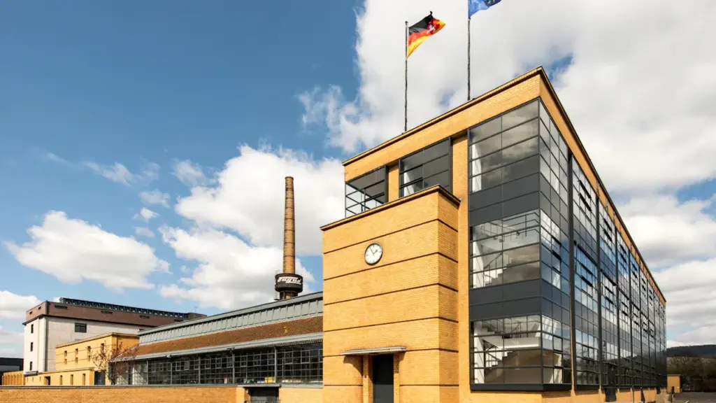 Modernes Industriegebäude mit deutscher Flagge bei strahlendem Sonnenschein und blauem Himmel.