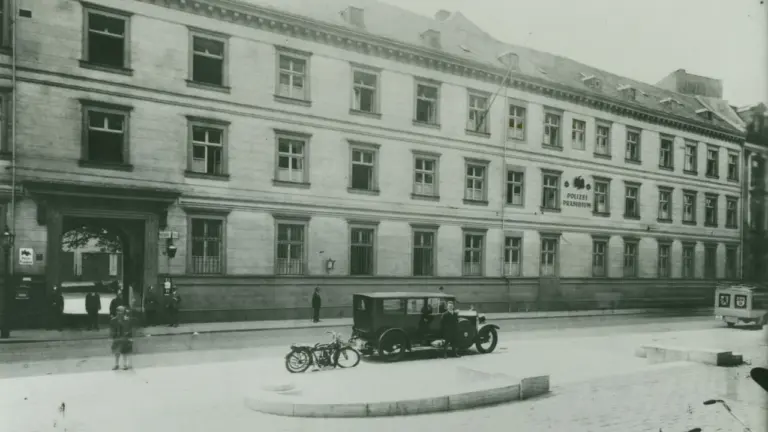 Historisches Gebäude des Polizeipräsidiums mit einem alten Auto und einem Motorrad auf dem Vorplatz.