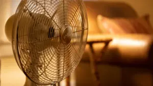Ein eingeschalteter Standventilator sorgt an einem heißen Sommertag für Abkühlung in einem Wohnraum.