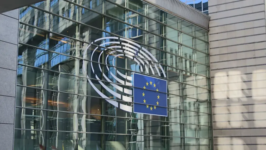 Glasfassade des Europäischen Parlaments mit dem offiziellen Europa-Logo bei Tageslicht.