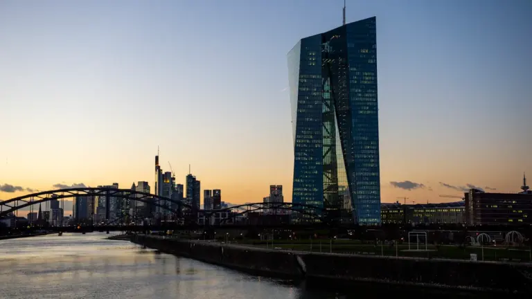 Blick auf das EZB-Gebäude und die Frankfurter Skyline bei Sonnenuntergang über dem Main.