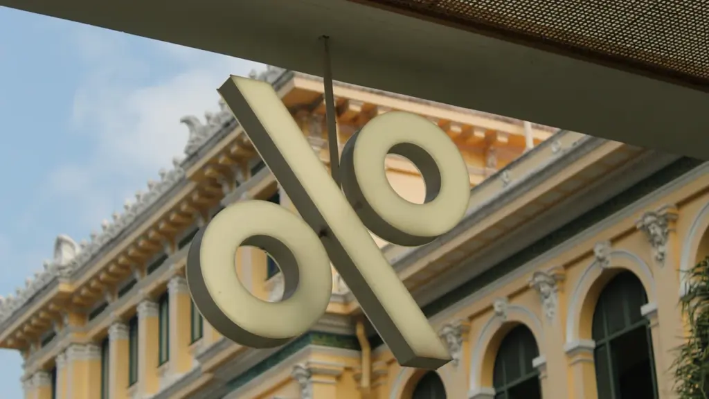 Ein großes Prozentzeichen hängt vor einem historischen Bankgebäude als Symbol für EZB-Zinssätze.