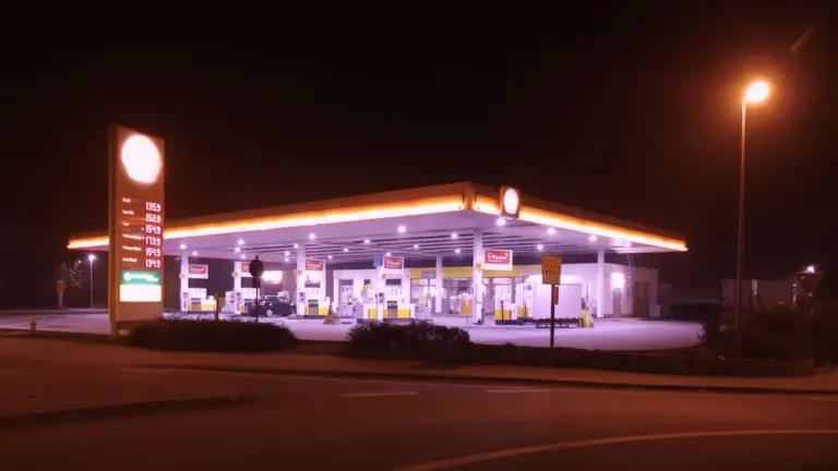 Beleuchtete Tankstelle bei Nacht mit gut sichtbarer Preistafel für den Kraftstoffvergleich.
