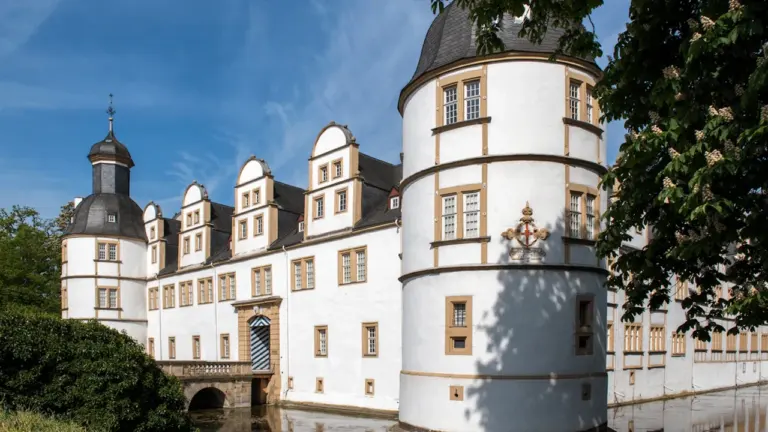 Historisches Schloss Neuhaus in Paderborn mit Brücke vor dem Eingang bei blauem Himmel