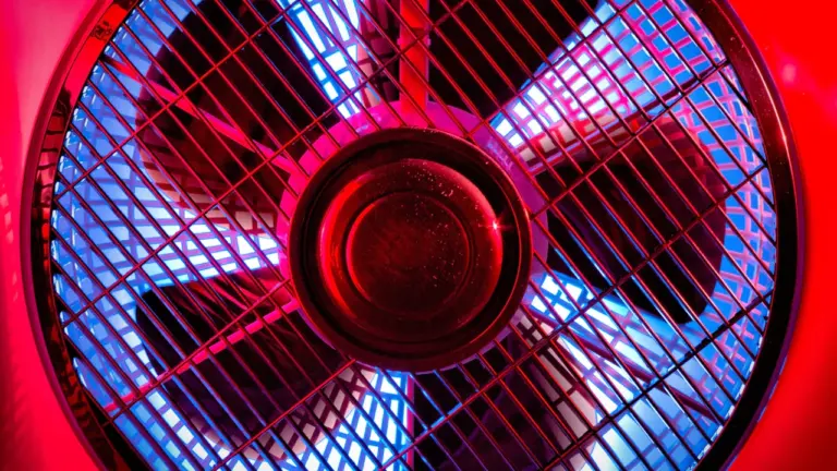 Ein Ventilator auf einem Holztisch bei stimmungsvoller Beleuchtung im Innenraum.