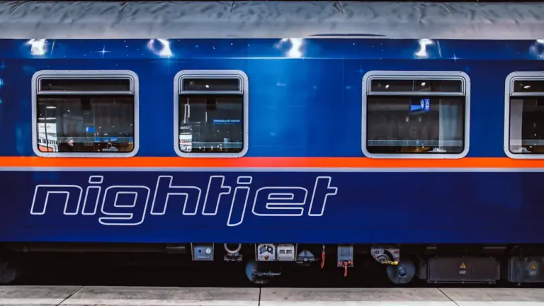 Ein blauer Nightjet-Zug steht abends zur Abfahrt an einem deutschen Bahnsteig bereit.