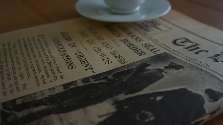 Historische Zeitung mit Schlagzeile zur Berliner Mauer und einer Kaffeetasse darauf.