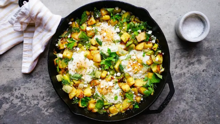 Eine gusseiserne Pfanne mit gebratenem Gemüse, Kirschtomaten und zerbröckeltem Feta.