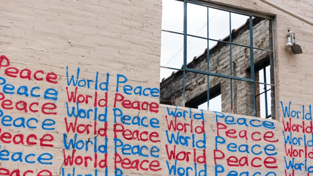 An der Hauswand steht in bunten Buchstaben mehrfach das Wort Weltfrieden geschrieben.