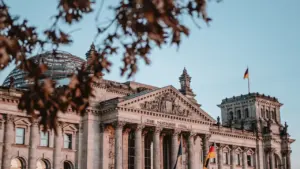 Das Reichstagsgebäude in Berlin bei Tageslicht mit wehender deutscher Flagge.