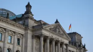 Das Reichstagsgebäude in Berlin unter blauem Himmel mit deutscher Flagge.