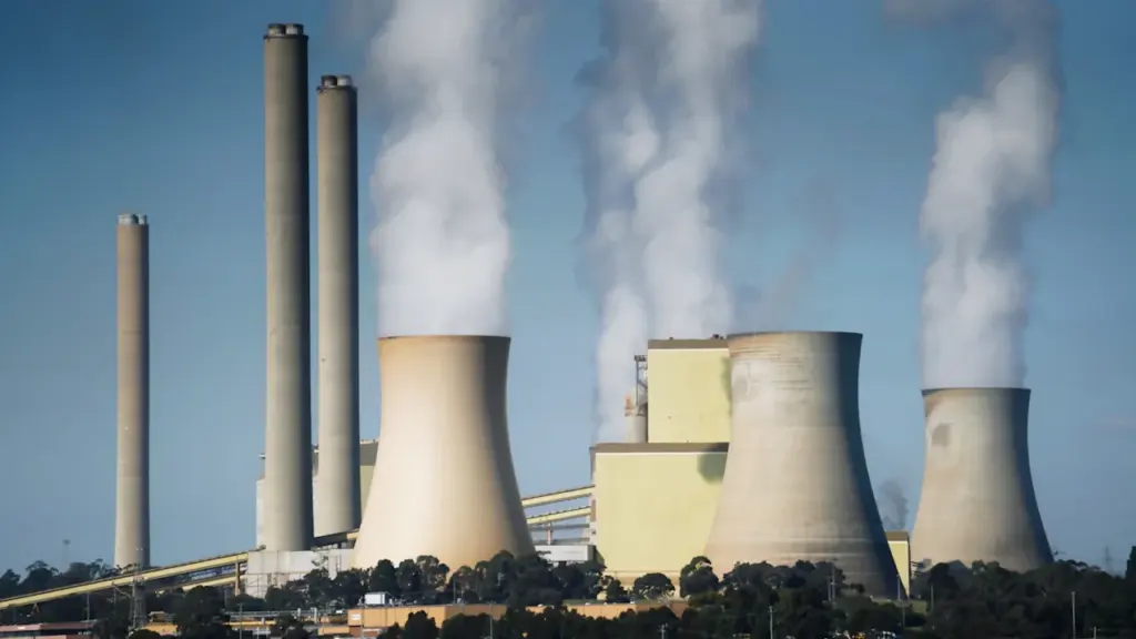 Industrielle Kühltürme stoßen bei blauem Himmel sichtbaren weißen Wasserdampf in die Luft.