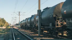 Ein Güterzug fährt auf den Schienen entlang einer ländlichen Bahnstrecke bei Tageslicht.