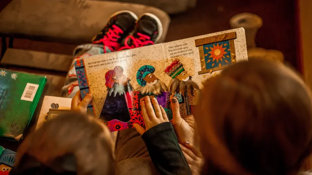 Zwei Kinder lesen gemeinsam in einem farbenfrohen Kinderbuch auf einem Sofa.