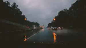 Autoverkehr bei regnerischem Wetter auf einer nassen Autobahn unter bewölktem Himmel.