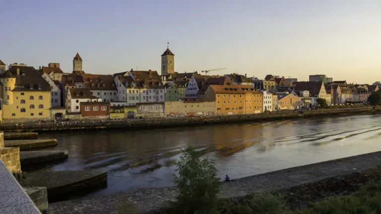 Historische Steinerne Brücke in Regensburg bei goldenem Abendlicht über der Donau.