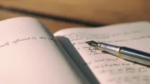 Füllfederhalter liegt auf einem aufgeschlagenen Notizbuch mit handgeschriebenen Notizen und Text.