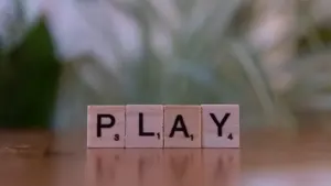 Holzwürfel mit den Buchstaben für das englische Wort Play auf einem Tisch.