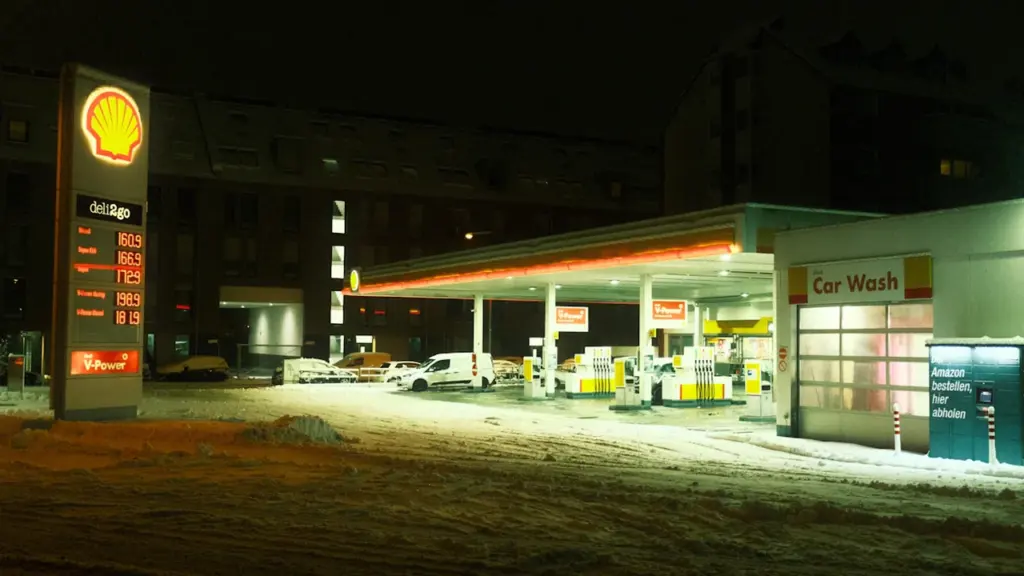 Eine beleuchtete Tankstelle bei Nacht mit Schnee auf dem Boden in Deutschland.