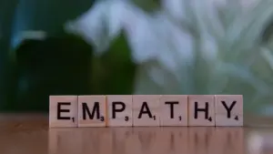 Holzwürfel mit den Buchstaben für das Wort Empathie auf einem Tisch.