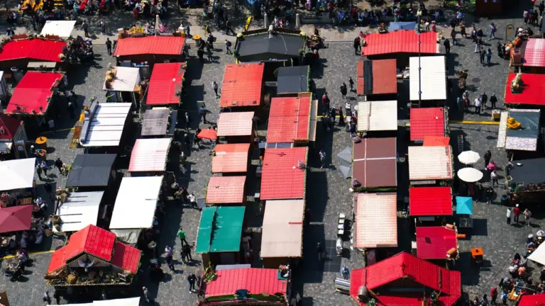 Vogelperspektive auf einen belebten Wochenmarkt mit zahlreichen bunten Marktständen im Freien.